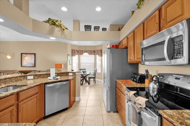 kitchen featuring light stone countertops, stainless steel appliances, sink, light tile patterned floors, and a high ceiling