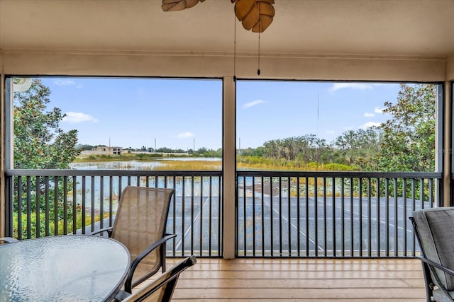 sunroom / solarium featuring ceiling fan, plenty of natural light, and a water view