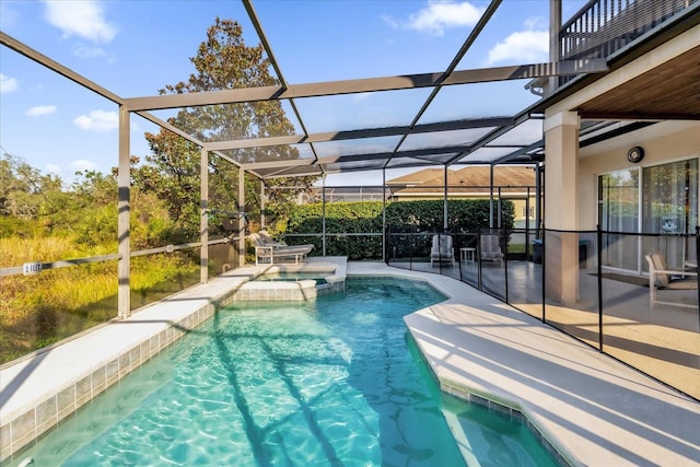 view of swimming pool with glass enclosure, an in ground hot tub, and a patio area