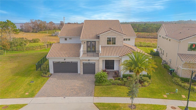 mediterranean / spanish-style home with a tiled roof, decorative driveway, a front yard, and fence