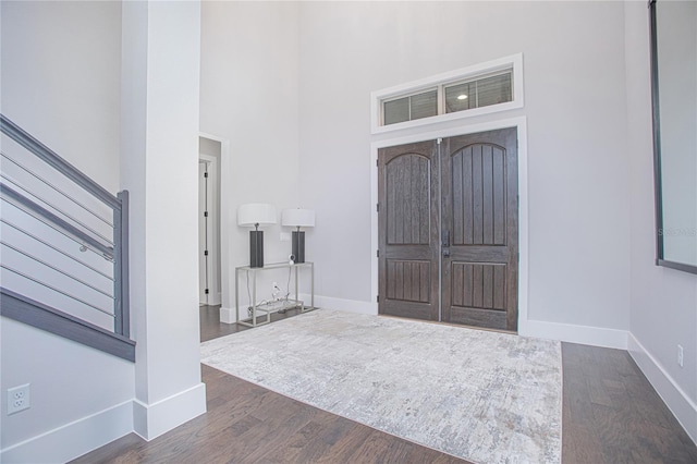 foyer entrance featuring dark wood finished floors, stairway, a high ceiling, and baseboards