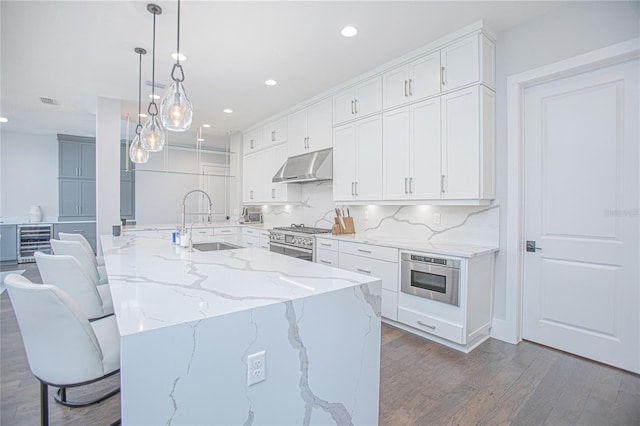 kitchen with under cabinet range hood, dark wood finished floors, white cabinets, and a sink