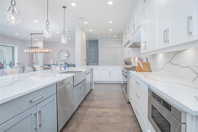 kitchen featuring light stone countertops, under cabinet range hood, recessed lighting, appliances with stainless steel finishes, and dark wood-style floors