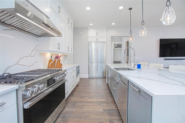 kitchen with high quality appliances, a sink, dark wood-style floors, white cabinetry, and wall chimney range hood