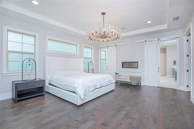 bedroom with visible vents, a barn door, recessed lighting, wood finished floors, and a raised ceiling