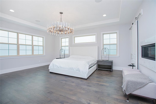 bedroom featuring dark wood finished floors, a tray ceiling, baseboards, and a chandelier