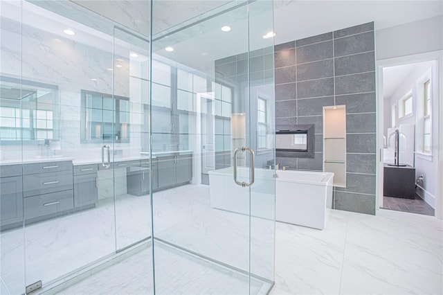 full bath featuring vanity, a freestanding tub, a shower stall, tile walls, and marble finish floor