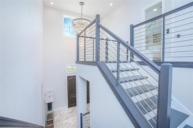 staircase featuring recessed lighting, baseboards, a high ceiling, and a chandelier