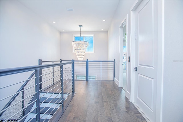 hall with wood finished floors, recessed lighting, an upstairs landing, and a chandelier