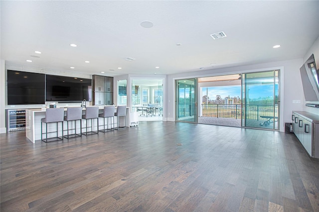 living room with recessed lighting, visible vents, dark wood-type flooring, and beverage cooler