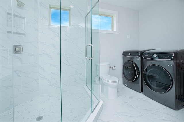 bathroom with marble finish floor, a healthy amount of sunlight, a shower stall, and washing machine and clothes dryer