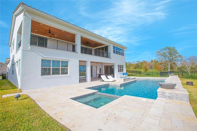 rear view of property featuring stucco siding, a ceiling fan, fence, a balcony, and a patio area