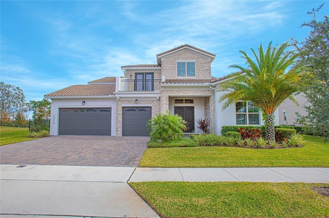 view of front of home with stucco siding, decorative driveway, a front yard, a balcony, and a tiled roof