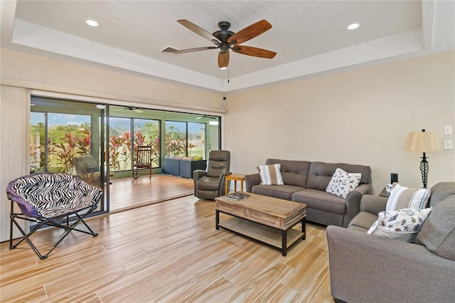 living room with ceiling fan and a raised ceiling