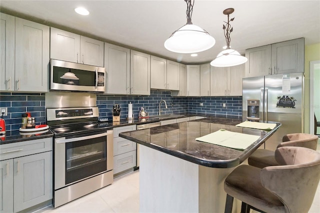 kitchen featuring gray cabinetry, decorative light fixtures, decorative backsplash, and stainless steel appliances