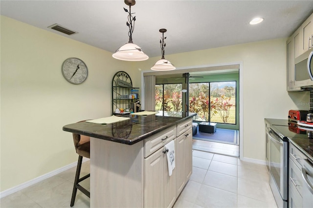 kitchen with a center island, hanging light fixtures, a breakfast bar area, light tile patterned floors, and stainless steel appliances