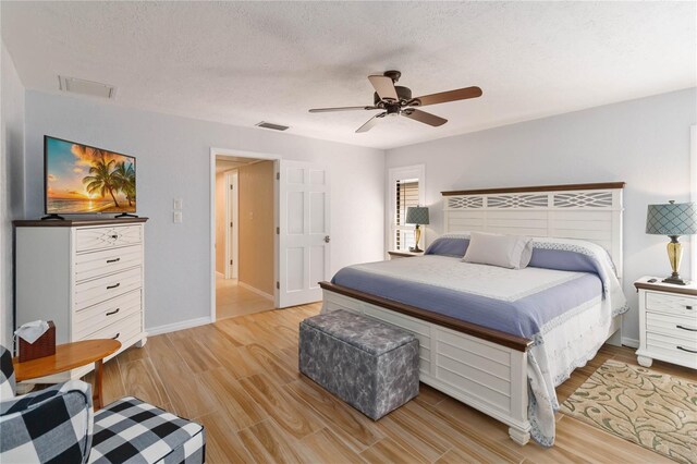 bedroom featuring a textured ceiling, light hardwood / wood-style floors, and ceiling fan