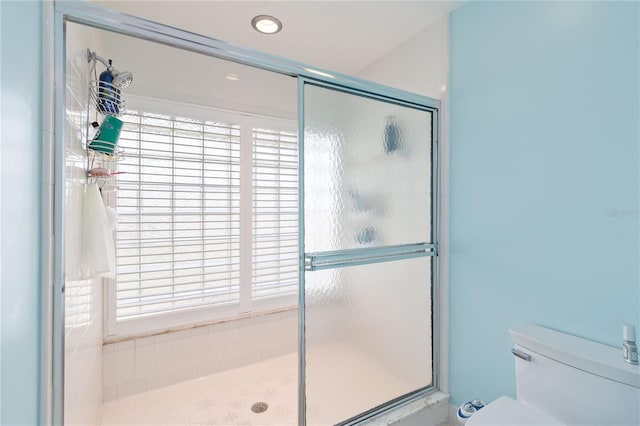 bathroom featuring toilet and a shower with shower door