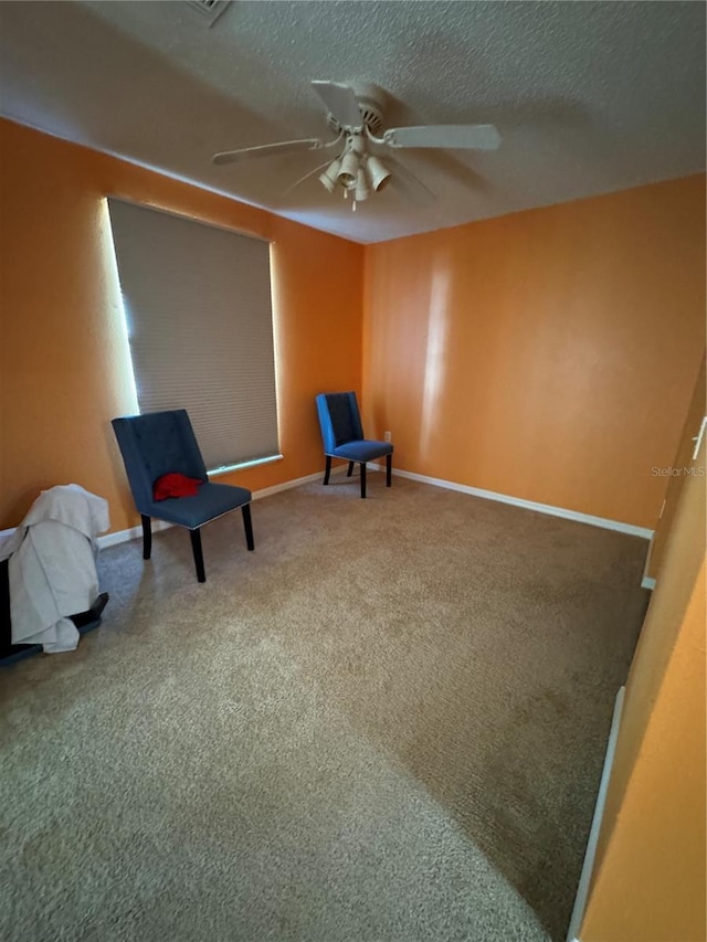 living area with carpet, ceiling fan, and a textured ceiling