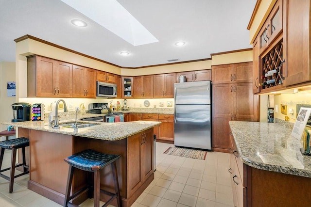 kitchen with a skylight, sink, stainless steel appliances, kitchen peninsula, and a breakfast bar