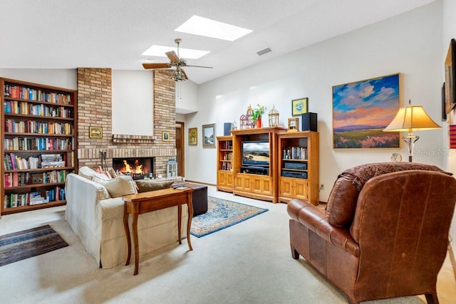 carpeted living room with lofted ceiling with skylight, ceiling fan, and a brick fireplace