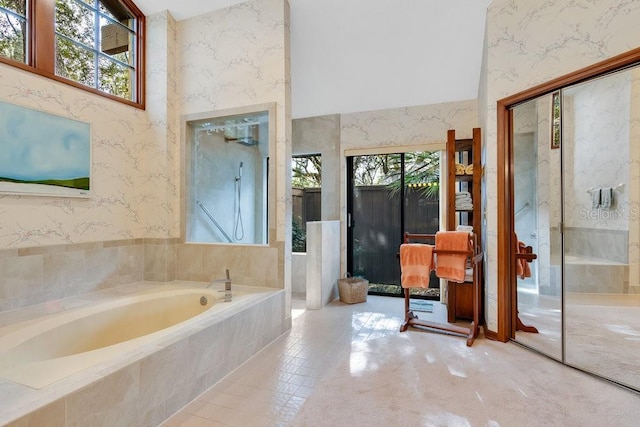 bathroom featuring a relaxing tiled tub and a towering ceiling