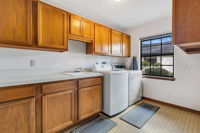 washroom with a textured ceiling, cabinets, independent washer and dryer, and sink