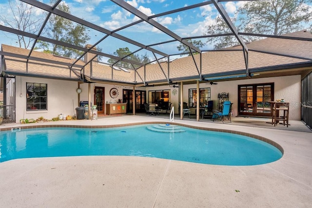 view of swimming pool with glass enclosure, ceiling fan, and a patio