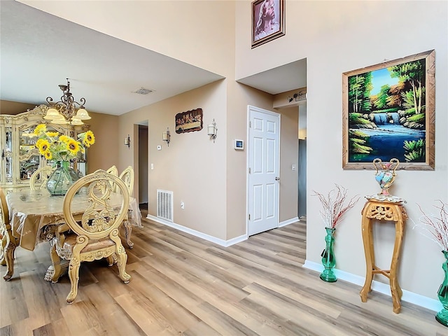 dining area with light hardwood / wood-style flooring and a chandelier