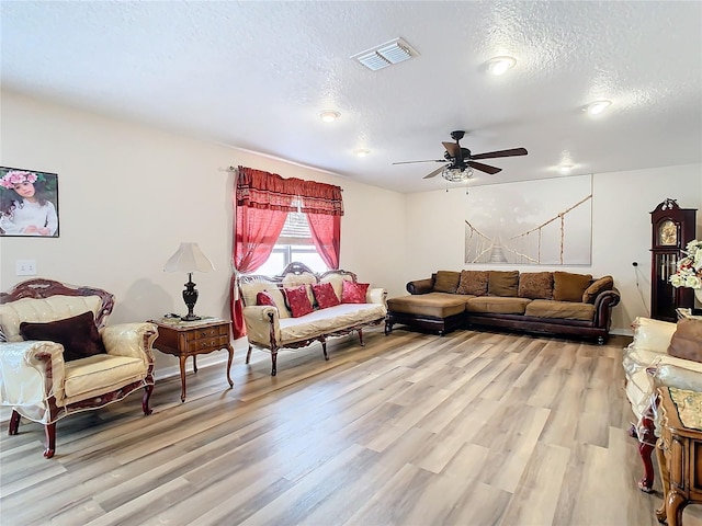 living room with ceiling fan, light hardwood / wood-style floors, and a textured ceiling