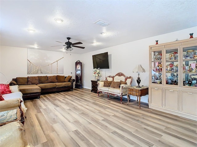 living room with ceiling fan, light hardwood / wood-style flooring, and a textured ceiling