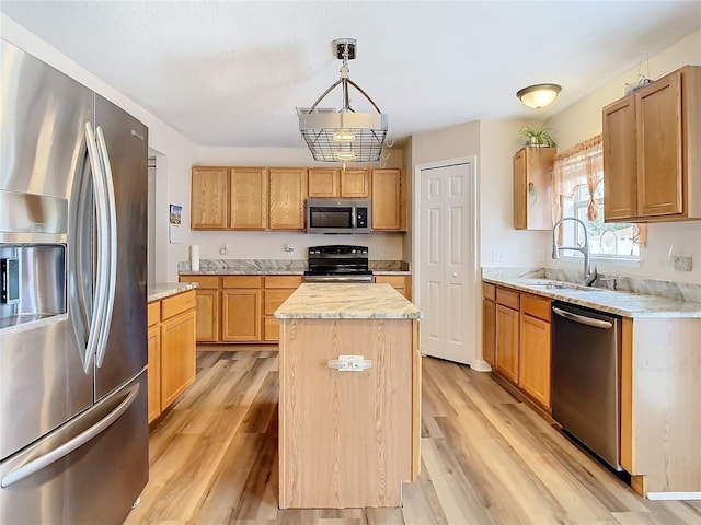 kitchen with pendant lighting, sink, light hardwood / wood-style floors, a kitchen island, and stainless steel appliances