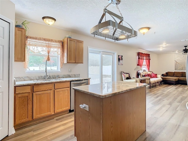 kitchen with a wealth of natural light, a center island, sink, stainless steel dishwasher, and light hardwood / wood-style floors