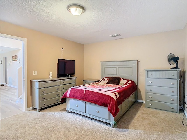 bedroom with light colored carpet and a textured ceiling