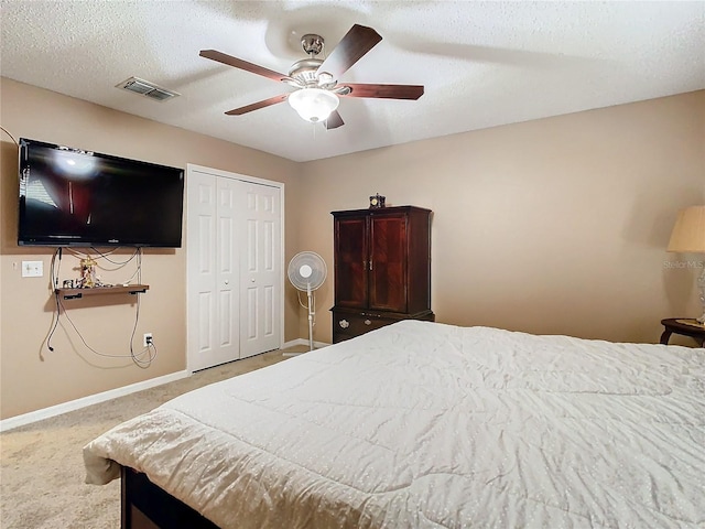 bedroom featuring carpet flooring, ceiling fan, a closet, and a textured ceiling