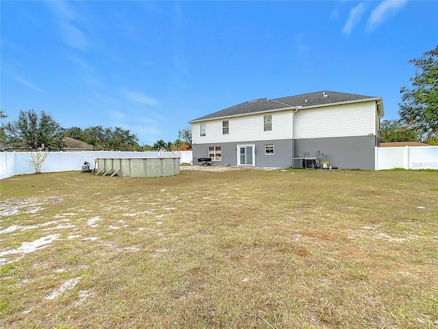 rear view of property with a yard, a fenced in pool, and cooling unit