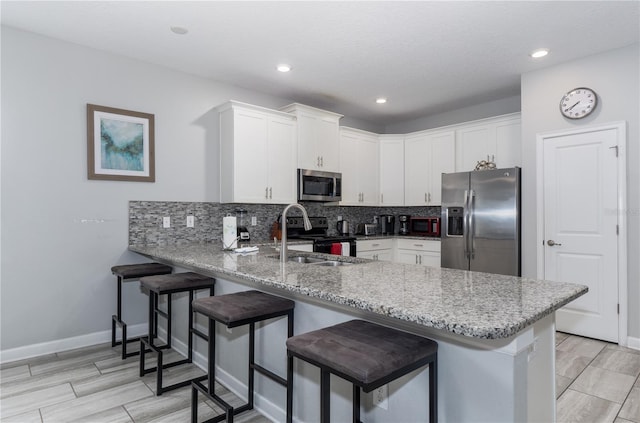 kitchen featuring white cabinets, light stone counters, kitchen peninsula, and stainless steel appliances