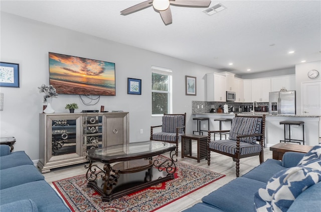 living room featuring ceiling fan, sink, and a textured ceiling