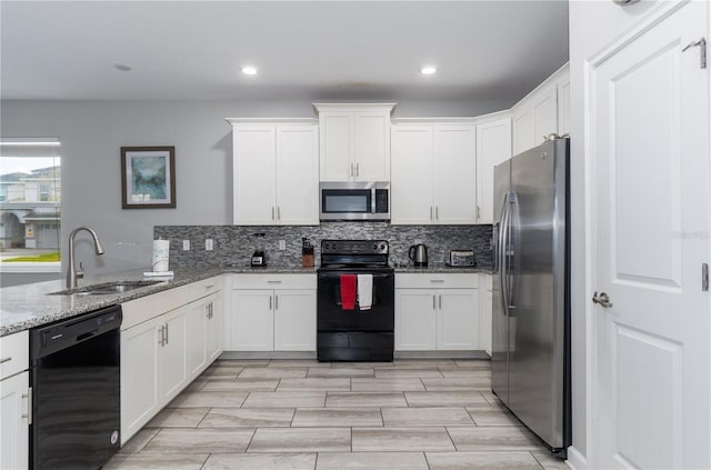 kitchen featuring black appliances, sink, light stone countertops, tasteful backsplash, and white cabinetry