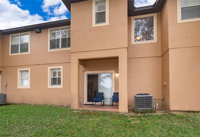 back of house with central AC unit, a patio area, and a lawn