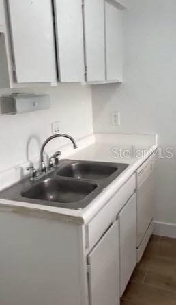 kitchen featuring white cabinets, dark wood-type flooring, dishwasher, and sink