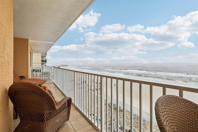 balcony with a water view and a view of the beach