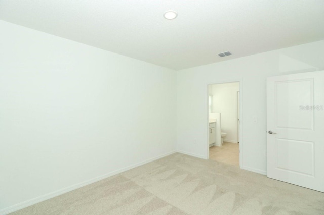 unfurnished bedroom with connected bathroom and light carpet