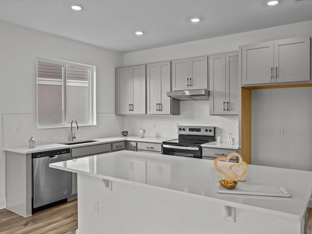 kitchen with gray cabinetry, sink, stainless steel appliances, and light hardwood / wood-style flooring