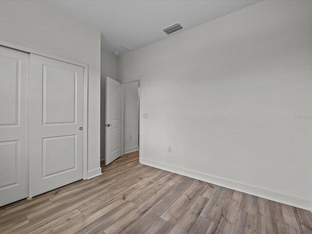 unfurnished bedroom featuring light hardwood / wood-style floors and a closet