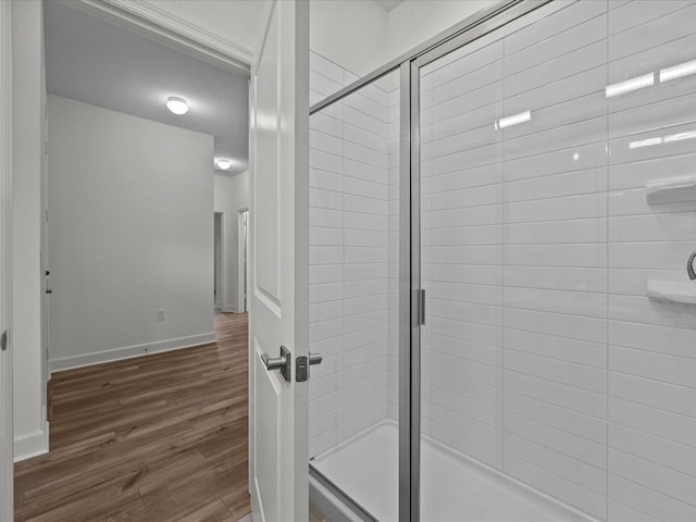 bathroom featuring a textured ceiling, wood-type flooring, and a shower with shower door