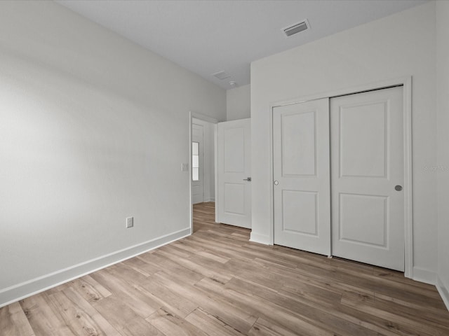 unfurnished bedroom with light hardwood / wood-style flooring and a closet