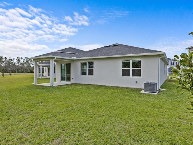 rear view of property featuring a patio, central AC unit, and a lawn