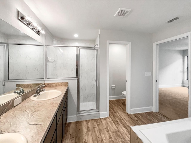 bathroom with a shower with door, vanity, wood-type flooring, and toilet