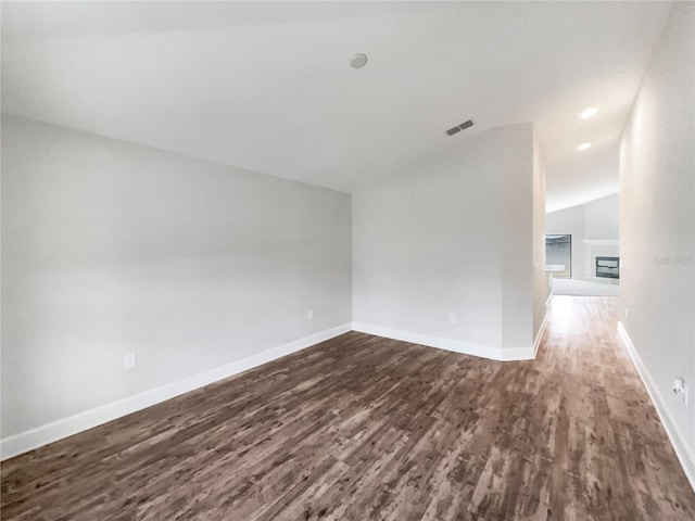 empty room with dark wood-type flooring and vaulted ceiling